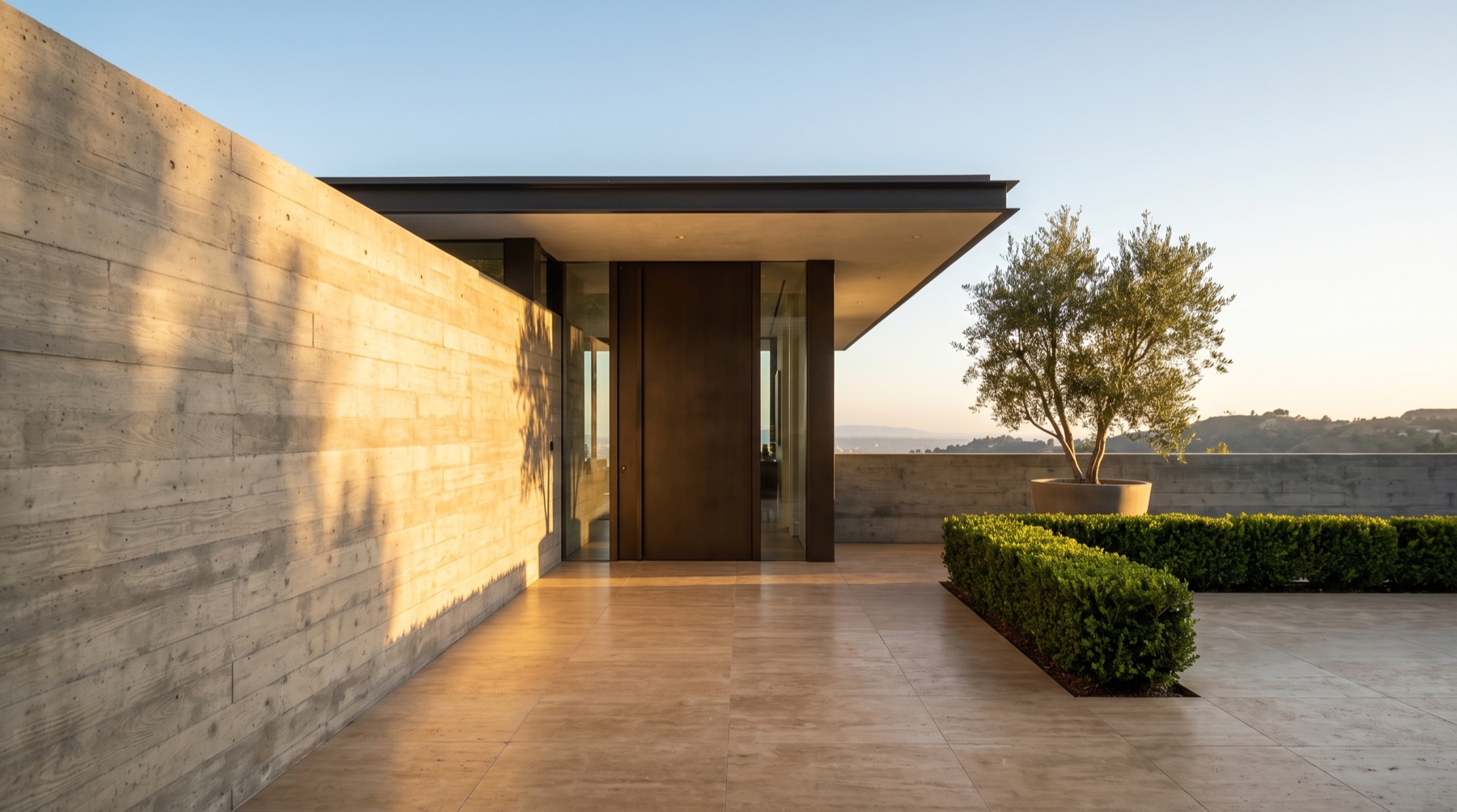Motor court with a board-formed concrete wall and a bronze pivot door